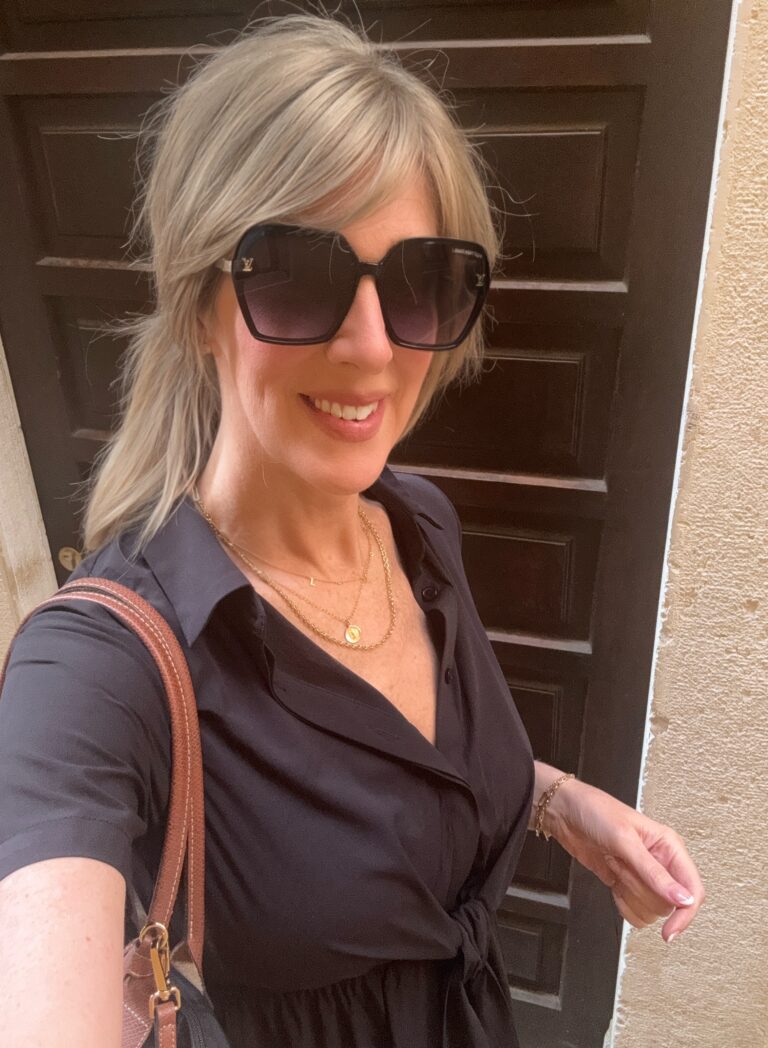 woman dressed in black dress sharing travel outfits and jewelry