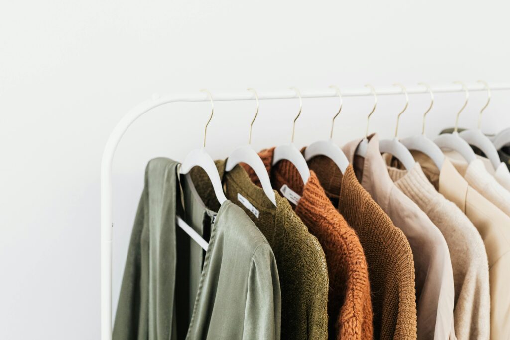 Capsule wardrobe showing neutral colors sweaters hanging on a clothing rod